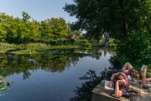 People laying and reading by the pond in Tivoli Park in Ljubljana