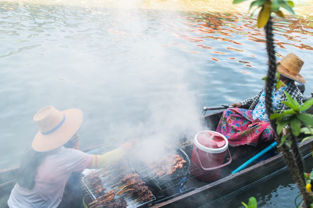 Two women selling fresh grilled food on their boat on the waterways