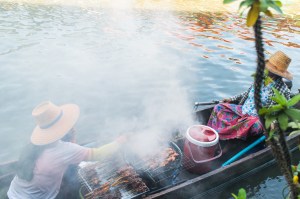 Two women selling fresh grilled food on their boat on the waterways